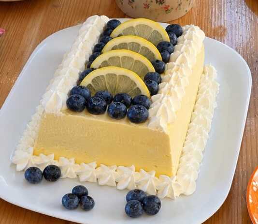 Αυθεντικό ιταλικό lemon semifreddo σερβιρισμένο σε πιατέλα, γαρνιρισμένο με ροζέτες σαντιγί, φρέσκα μύρτιλα και λεπτές ροδέλες λεμονιού