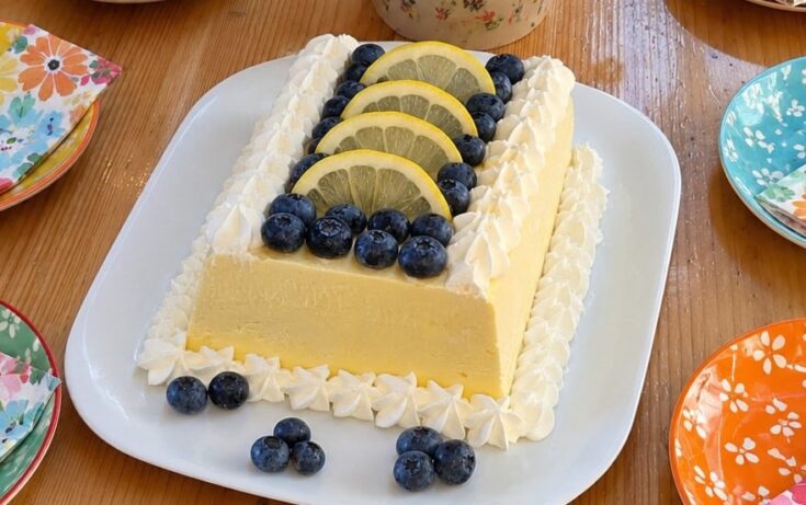 Αυθεντικό ιταλικό lemon semifreddo σερβιρισμένο σε πιατέλα, γαρνιρισμένο με ροζέτες σαντιγί, φρέσκα μύρτιλα και λεπτές ροδέλες λεμονιού