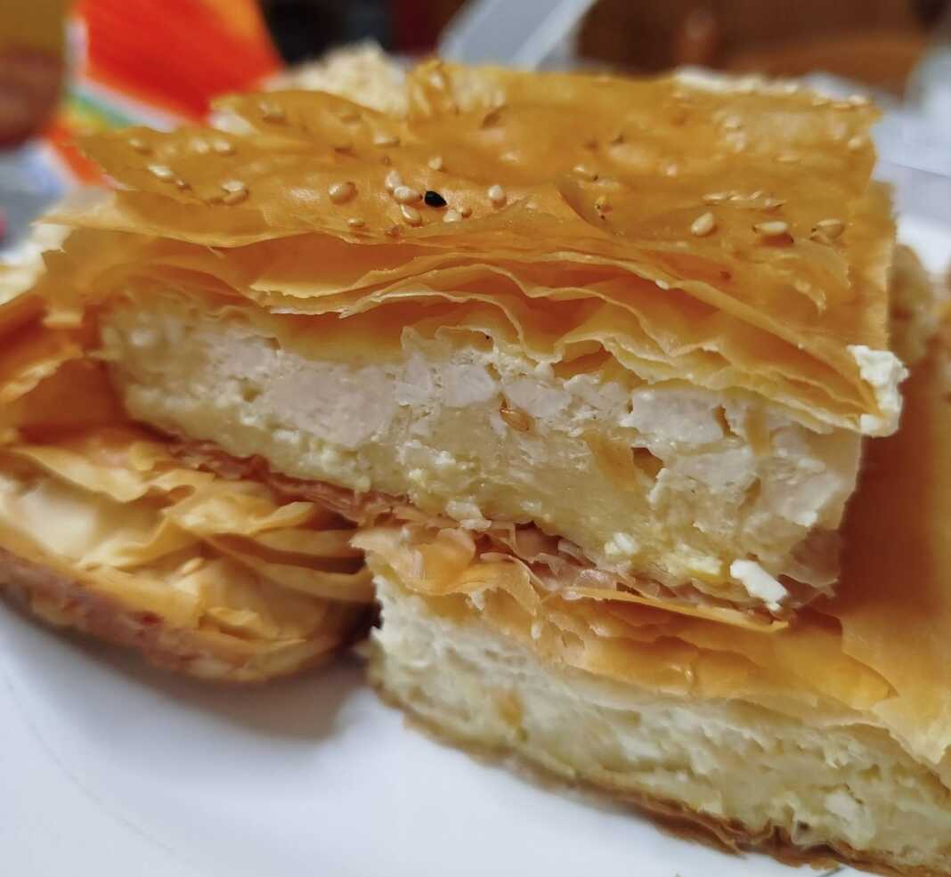 Κομμάτι από ζουμερή τυρόπιτα σουφλέ στο πιάτο, που δείχνει την αφράτη γέμιση τυριού και τα ροδοκόκκινα τραγανά φύλλα στην επιφάνεια