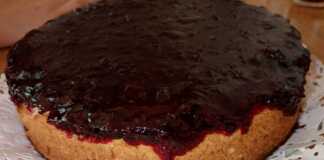 Ένα κομψό ψητό cheesecake σε πιατέλα, με μια πλούσια, λαμπερή κατακόκκινη σάλτσα από φράουλες και μούρα να απλώνεται ομοιόμορφα στην επιφάνειά του
