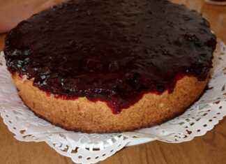 Ένα κομψό ψητό cheesecake σε πιατέλα, με μια πλούσια, λαμπερή κατακόκκινη σάλτσα από φράουλες και μούρα να απλώνεται ομοιόμορφα στην επιφάνειά του