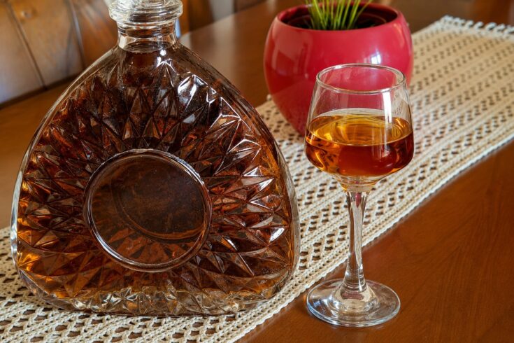 Γυάλινο μπουκάλι και ποτήρι με σπιτικό λικέρ Αμαρέτο και αμύγδαλα