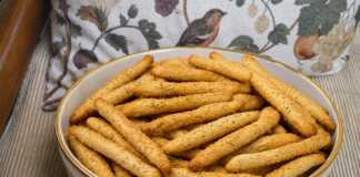 Τραγανά Sticks με σουσάμι και αρώματα μπαχαρικών Πιατέλα με στρογγυλά μπισκότα καλυμμένα με καβουρδισμένο σουσάμι δίπλα σε φλιτζάνι τσάι