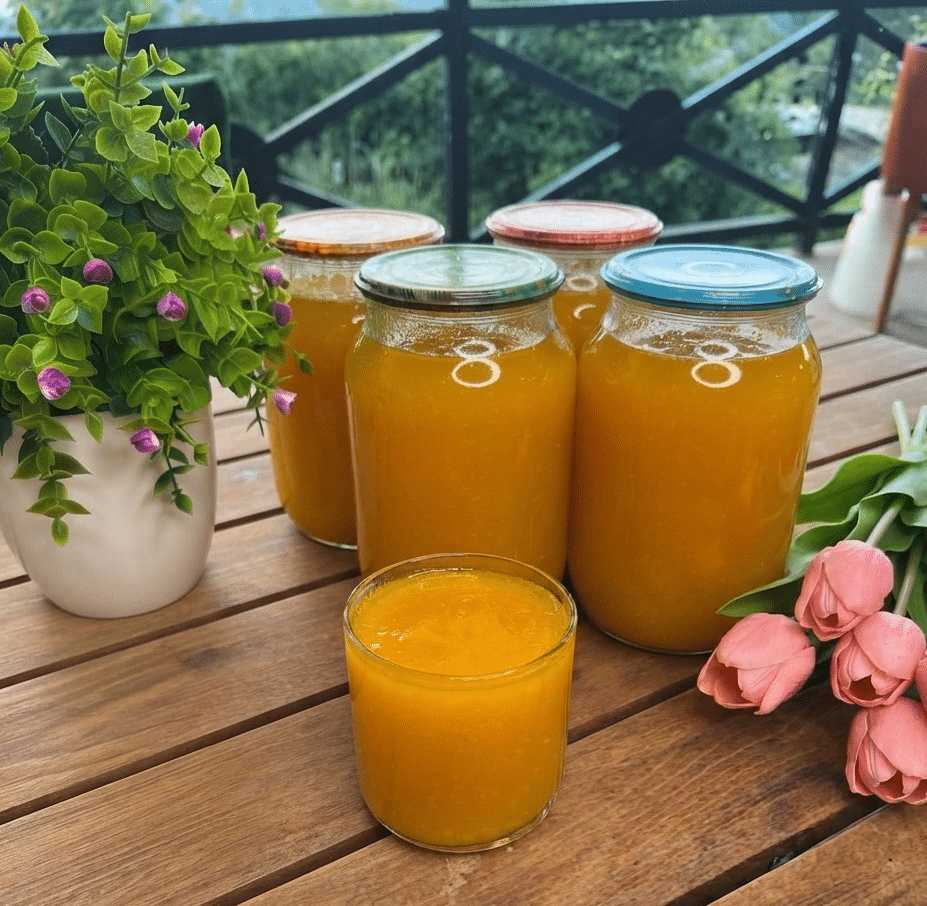 ximos rodakino Γυάλινα βάζα και ποτήρι γεμάτα με πλούσιο, πορτοκαλί σπιτικό χυμό ροδάκινο δίπλα σε φρέσκα φρούτα